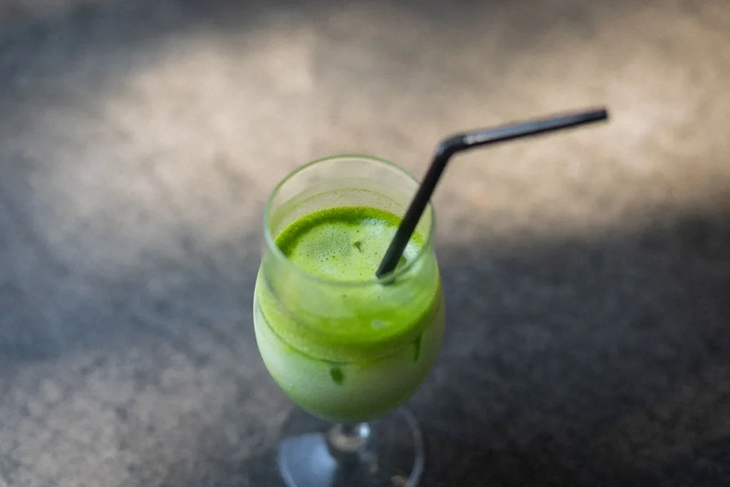 Iced Matcha Drink in einem Glas mit Strohhalm, kalte Matcha-Latte-Variante für den Sommer
